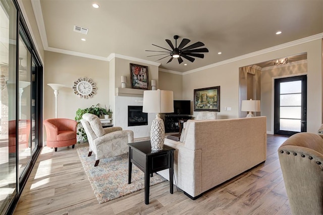 living room featuring ceiling fan, ornamental molding, and light hardwood / wood-style floors