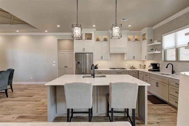 kitchen with stainless steel appliances, sink, a kitchen island with sink, and decorative light fixtures