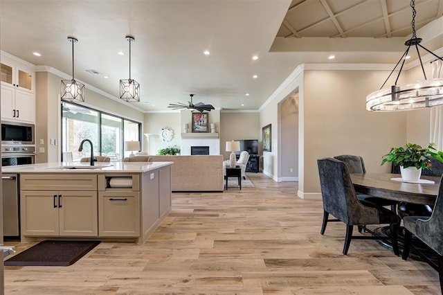 kitchen featuring sink, light hardwood / wood-style flooring, white cabinetry, stainless steel appliances, and decorative light fixtures