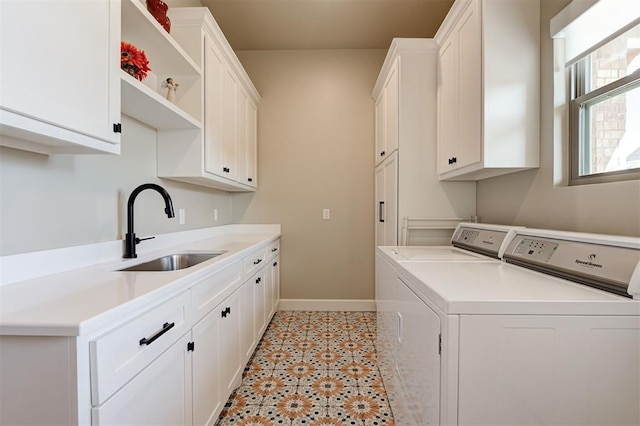 clothes washing area with sink, washer and clothes dryer, and cabinets