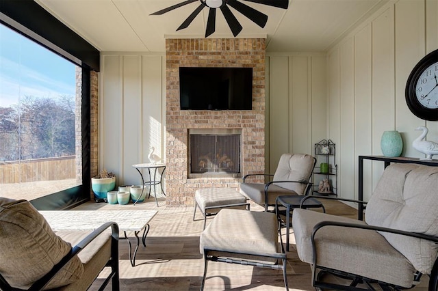 sunroom / solarium featuring a brick fireplace and ceiling fan