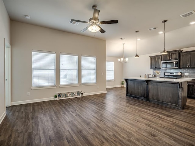 kitchen featuring dark hardwood / wood-style floors, pendant lighting, stainless steel appliances, dark brown cabinets, and a center island with sink