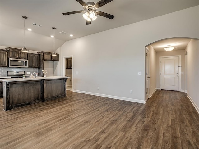 kitchen with appliances with stainless steel finishes, backsplash, dark hardwood / wood-style floors, dark brown cabinetry, and decorative light fixtures