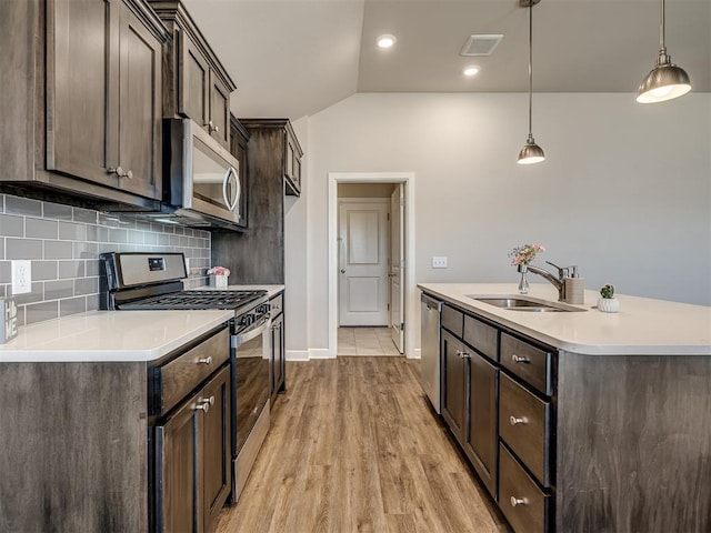 kitchen with pendant lighting, sink, appliances with stainless steel finishes, backsplash, and dark brown cabinets