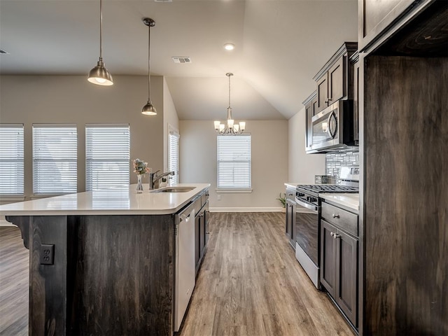 kitchen featuring dark brown cabinetry, sink, decorative light fixtures, a center island with sink, and appliances with stainless steel finishes