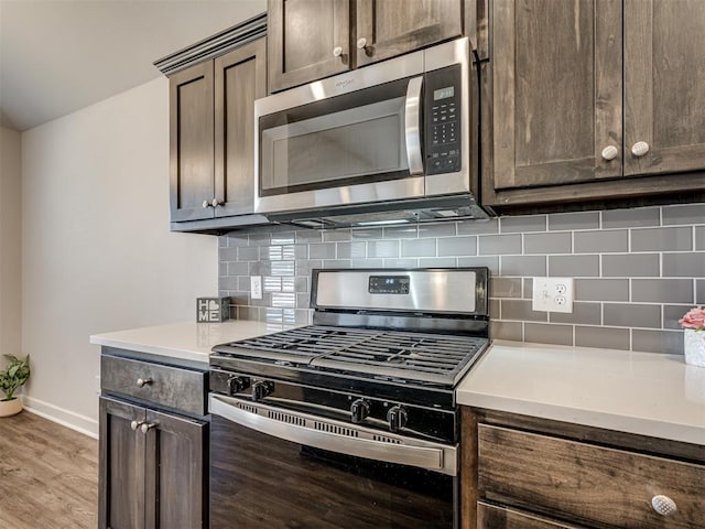 kitchen with dark brown cabinetry, decorative backsplash, light hardwood / wood-style floors, and appliances with stainless steel finishes