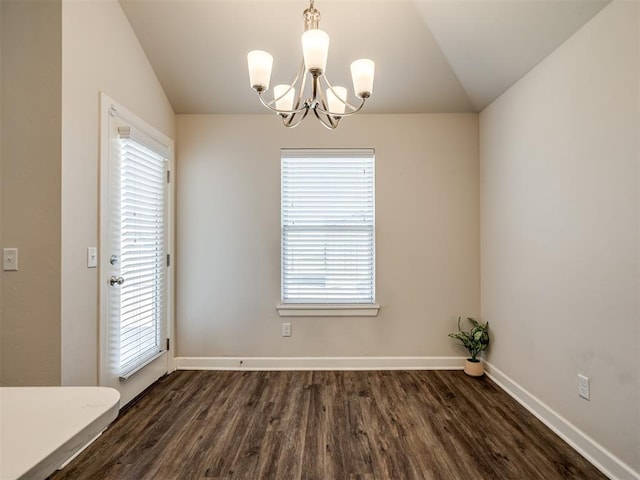 unfurnished dining area featuring dark wood-type flooring, plenty of natural light, an inviting chandelier, and vaulted ceiling