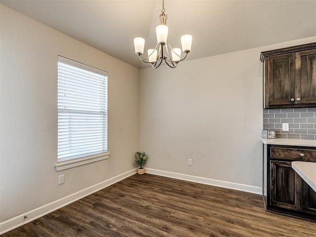 unfurnished dining area featuring dark wood-type flooring and a chandelier