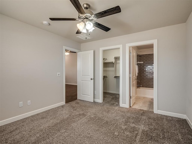 unfurnished bedroom featuring a spacious closet, light colored carpet, ensuite bath, and a closet