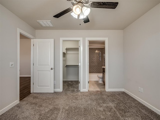 unfurnished bedroom with ceiling fan, connected bathroom, a spacious closet, light colored carpet, and a closet