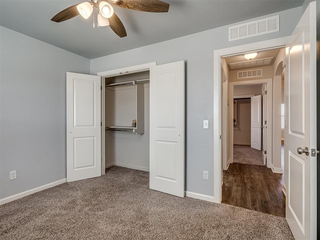 unfurnished bedroom featuring dark carpet, a closet, and ceiling fan