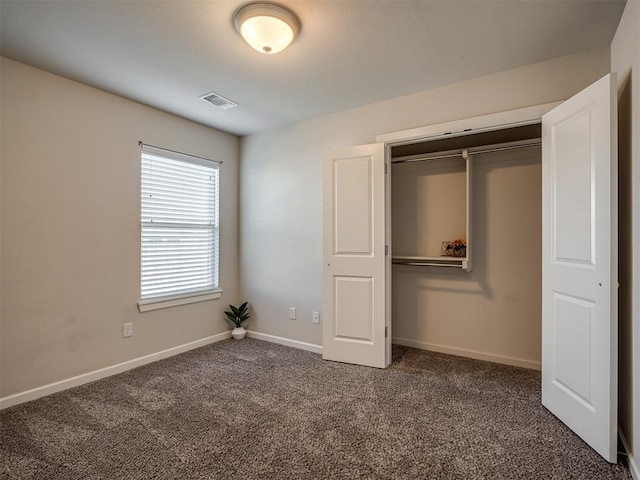 unfurnished bedroom with a closet and dark colored carpet