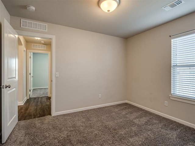 unfurnished room featuring dark carpet