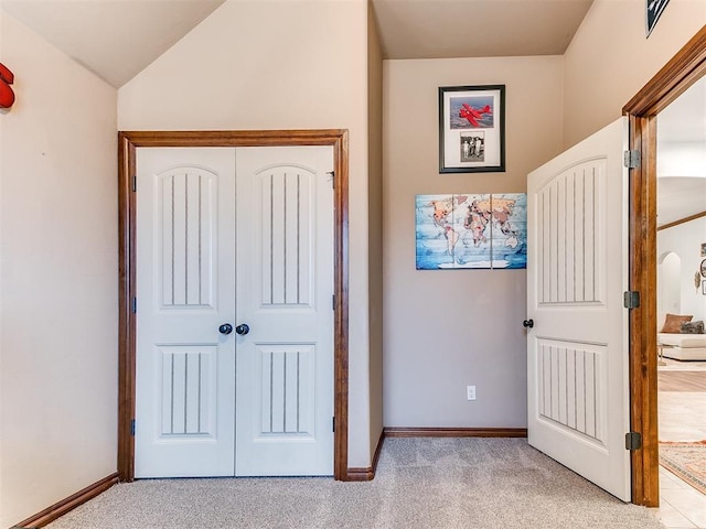 unfurnished bedroom featuring vaulted ceiling, light colored carpet, and a closet