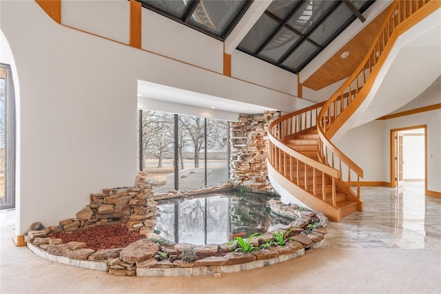 stairs featuring a towering ceiling, marble finish floor, and baseboards