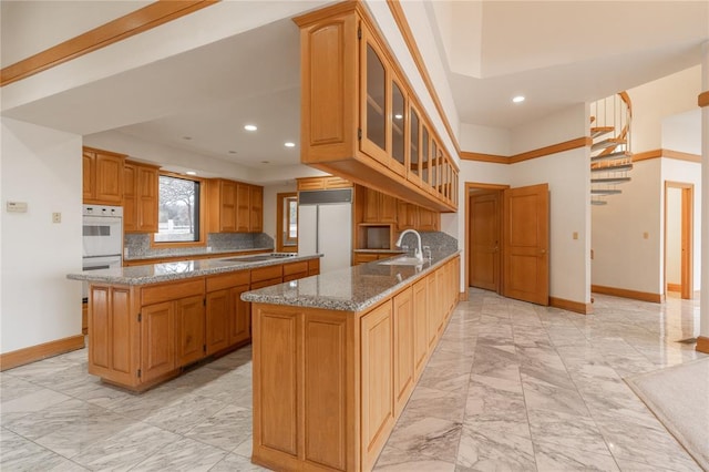 kitchen featuring a center island, light stone counters, kitchen peninsula, decorative backsplash, and built in fridge