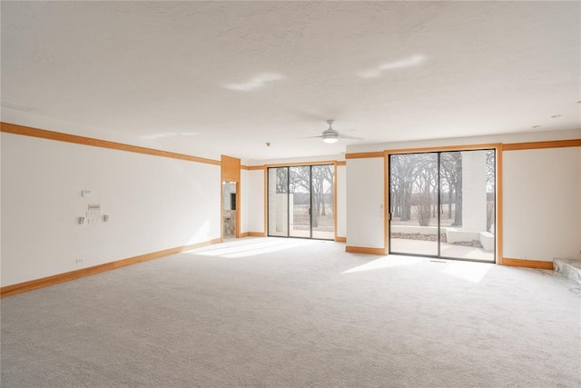 unfurnished room with light carpet, ceiling fan, baseboards, and a textured ceiling