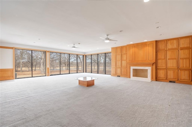 unfurnished living room featuring recessed lighting, visible vents, a premium fireplace, light carpet, and ceiling fan