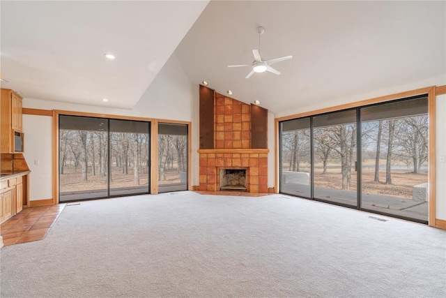 unfurnished living room featuring light carpet, high vaulted ceiling, a large fireplace, and ceiling fan