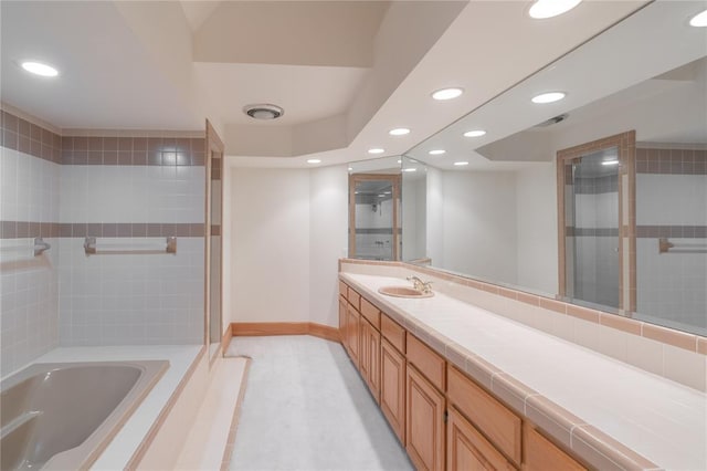 bathroom featuring recessed lighting, vanity, baseboards, a shower stall, and a bathtub