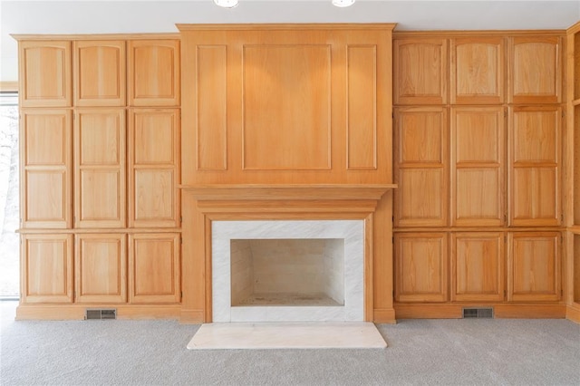 unfurnished living room featuring a fireplace, visible vents, and light colored carpet