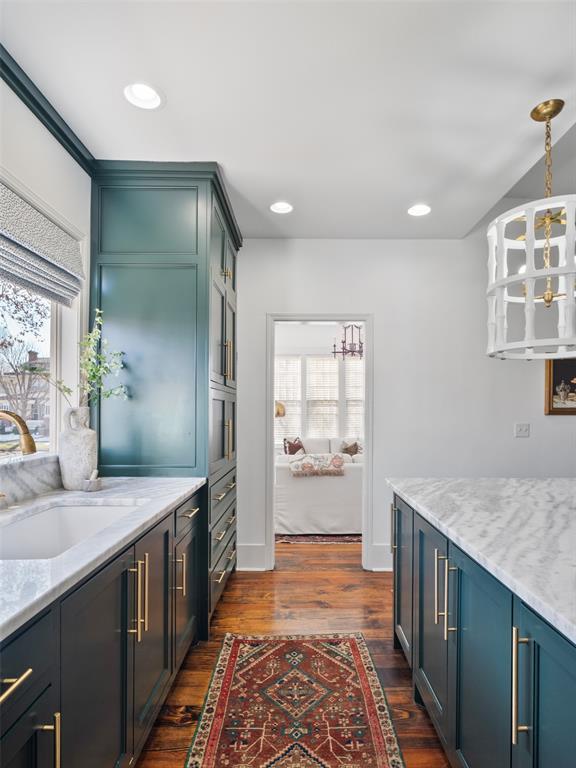 kitchen featuring sink, dark wood-type flooring, an inviting chandelier, blue cabinets, and decorative light fixtures