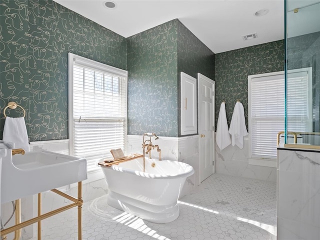 bathroom featuring a wealth of natural light and a tub to relax in