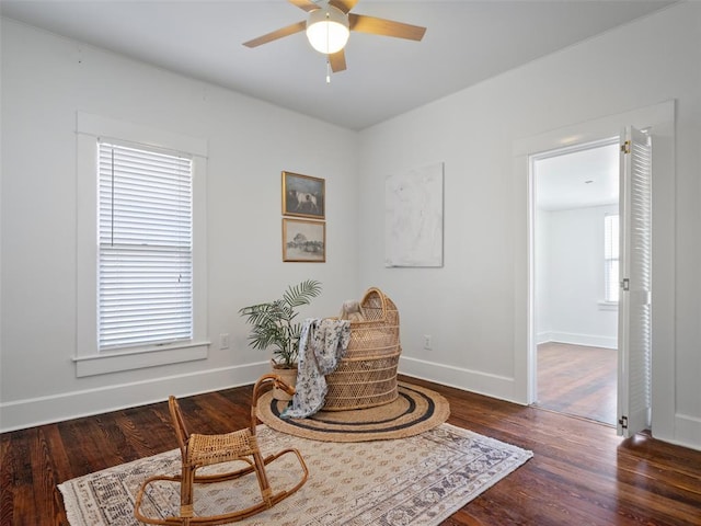 living area featuring dark hardwood / wood-style floors and ceiling fan