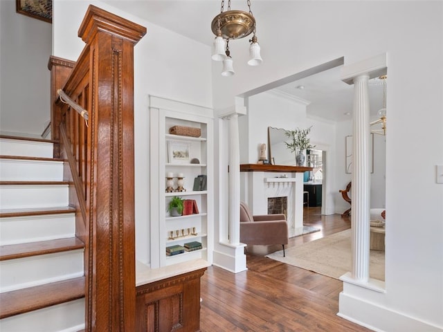 stairs with ornamental molding, wood-type flooring, decorative columns, and built in features