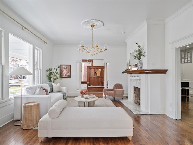 living room with dark wood-type flooring, ornamental molding, a fireplace, and a notable chandelier