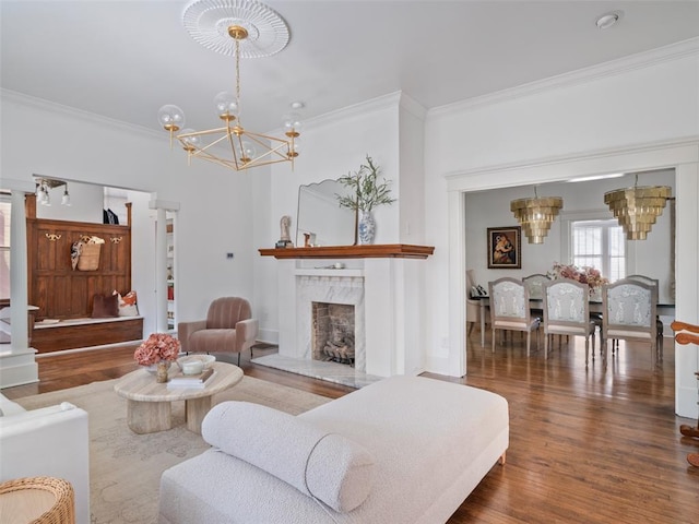 living room featuring an inviting chandelier, hardwood / wood-style flooring, a high end fireplace, and ornamental molding