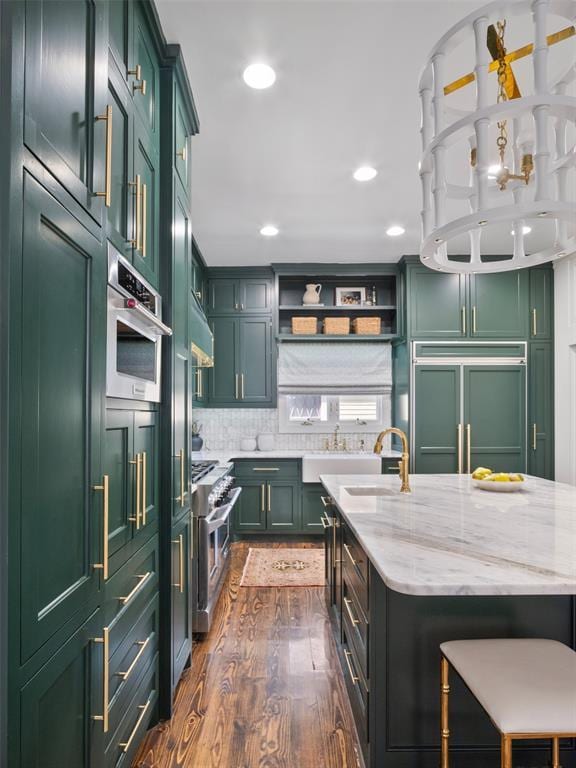 kitchen featuring sink, light stone countertops, high quality appliances, and green cabinets