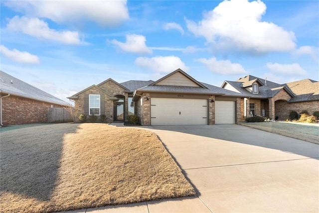 view of front of home with an attached garage, brick siding, a shingled roof, fence, and driveway