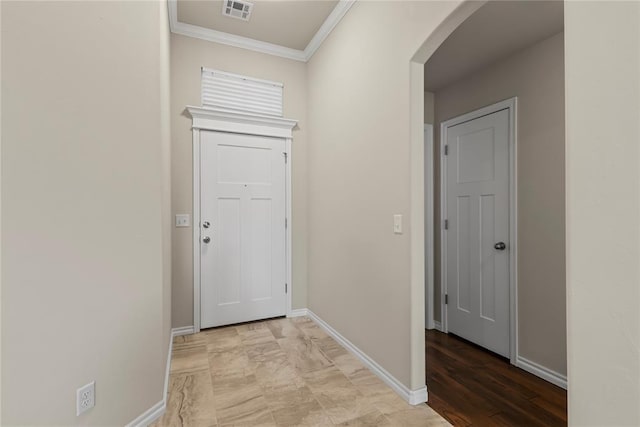 hall with arched walkways, ornamental molding, visible vents, and baseboards