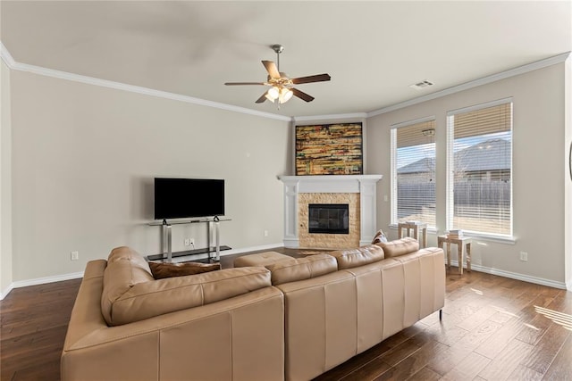 living room with ceiling fan, ornamental molding, dark hardwood / wood-style flooring, and a tiled fireplace