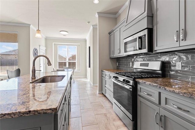 kitchen featuring gray cabinetry, appliances with stainless steel finishes, decorative light fixtures, and dark stone countertops