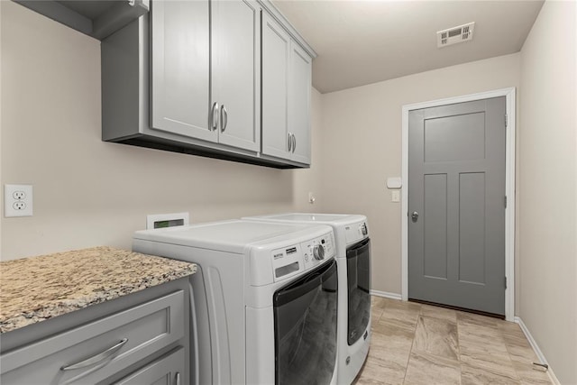 clothes washing area featuring cabinets and separate washer and dryer