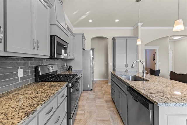 kitchen featuring arched walkways, light stone counters, appliances with stainless steel finishes, gray cabinetry, and a sink