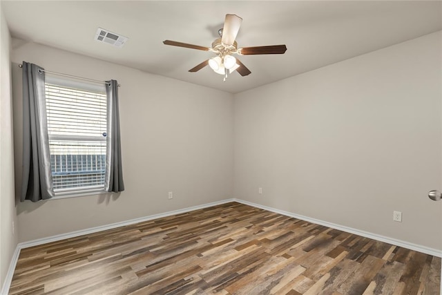 spare room with a ceiling fan, visible vents, baseboards, and wood finished floors