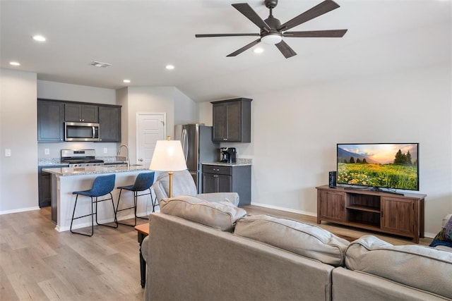 living room featuring ceiling fan, lofted ceiling, sink, and light hardwood / wood-style floors