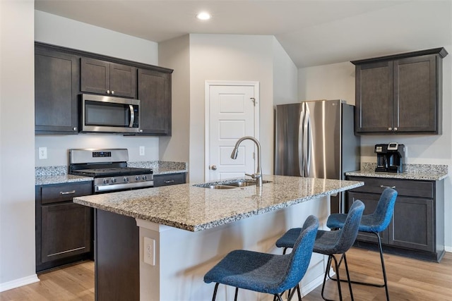 kitchen featuring appliances with stainless steel finishes, sink, a center island with sink, and light wood-type flooring