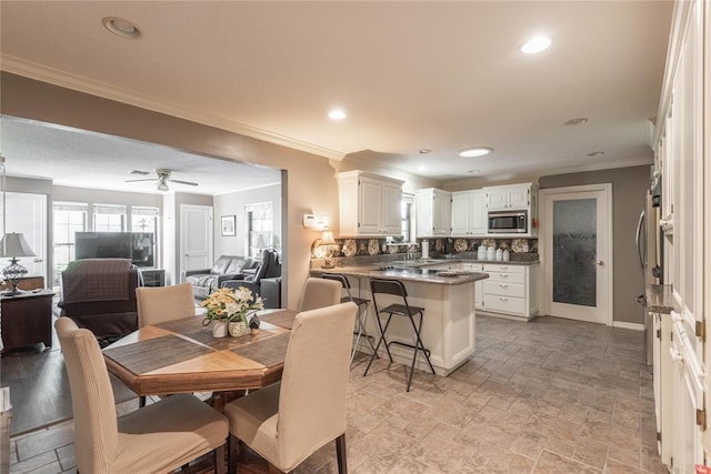 dining space with ceiling fan, ornamental molding, and sink