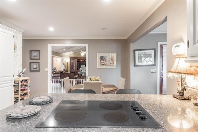 kitchen with crown molding, light stone counters, white cabinetry, black electric cooktop, and ceiling fan