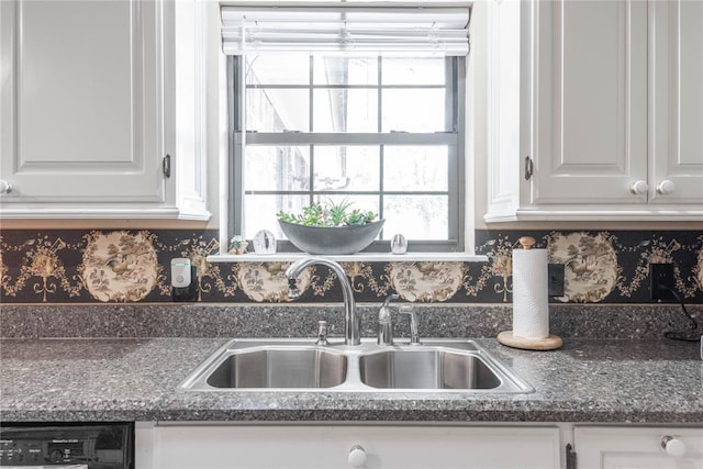 kitchen with backsplash, black dishwasher, sink, and white cabinets