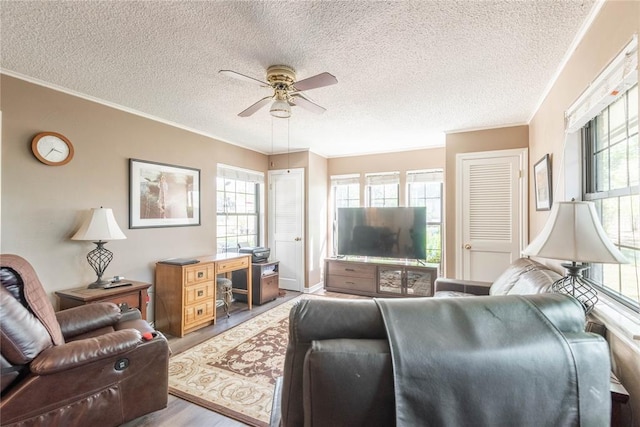 living room with wood-type flooring, ornamental molding, a wealth of natural light, and ceiling fan