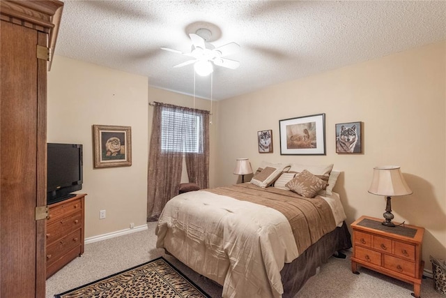 bedroom with ceiling fan, light colored carpet, and a textured ceiling