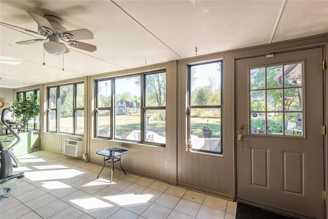 unfurnished sunroom featuring a wealth of natural light, a wall unit AC, and ceiling fan