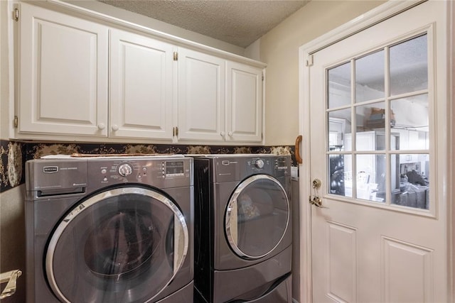 clothes washing area featuring cabinets, a textured ceiling, and independent washer and dryer