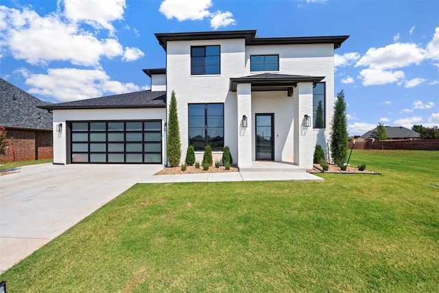 modern home featuring driveway, a front lawn, an attached garage, and brick siding