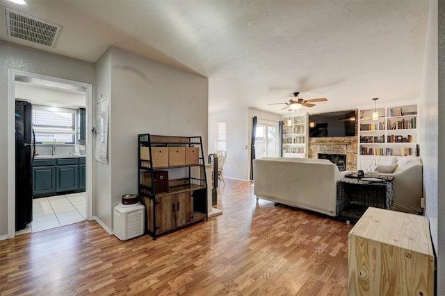 living room with sink, a textured ceiling, built in features, a fireplace, and hardwood / wood-style floors